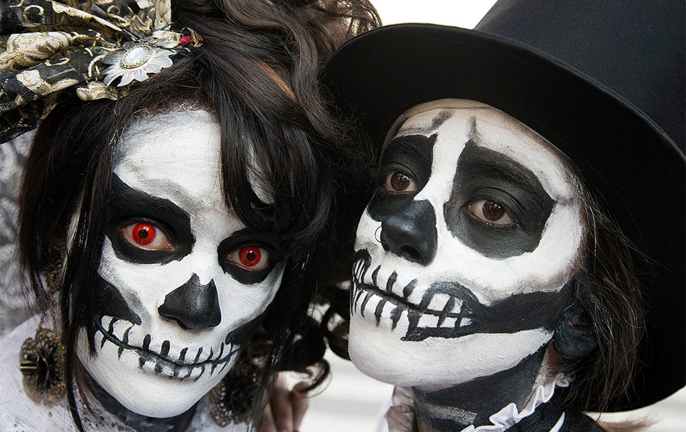 A woman and a man, painted up as calaveras or skull faces, pose for a photo during a Zombie Walk in Sao Paulo, Brazil.