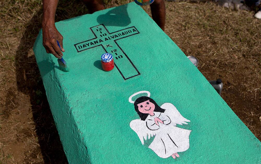 Ronald Alvarado applies a coat of fresh paint on his daughter`s grave at a cemetery in El Crucero on the outskirts of Managua, Nicaragua.