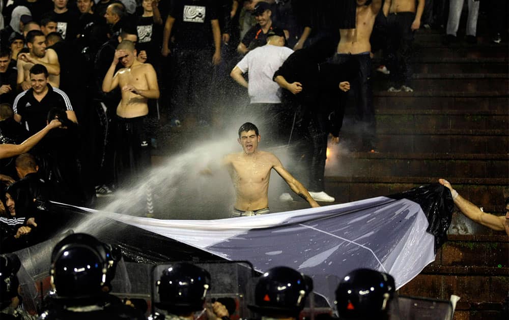 A Partizan Belgrade supporter is hit by a water cannon during his team`s Serbian league soccer game against arch rivals Red Star in Belgrade, Serbia.