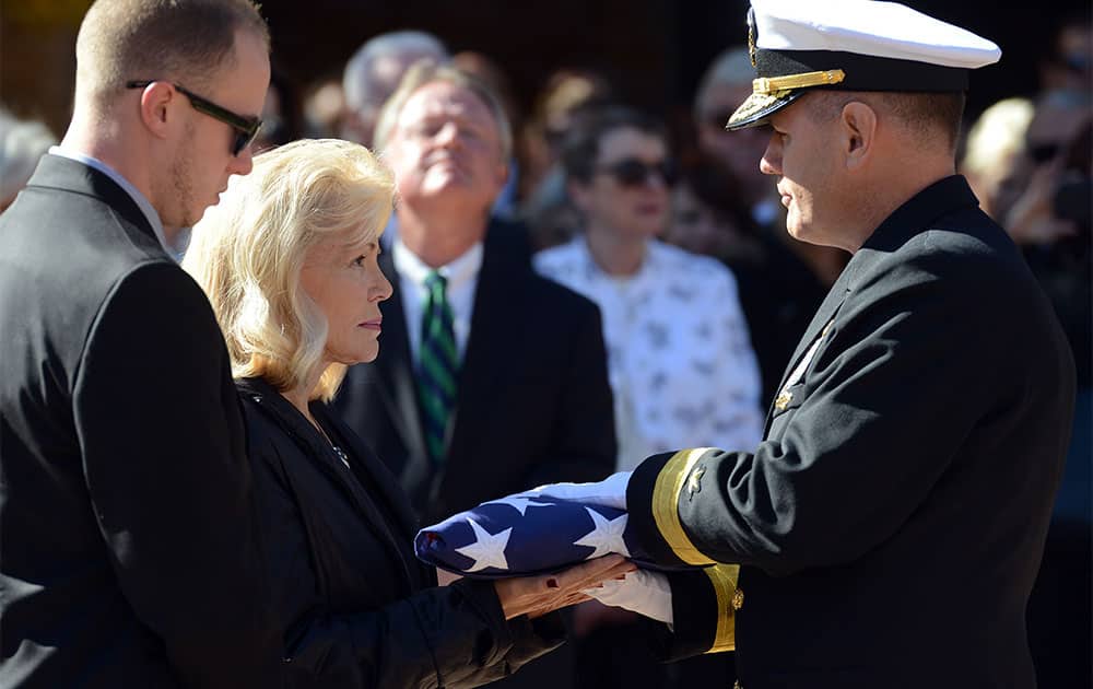 Patty Carpenter, left, receives the flag that was draped over her husband, astronaut Scott Carpenter`s casket from U.S. Navy Rear Adm. Thomas Bond in Boulder, Colo.