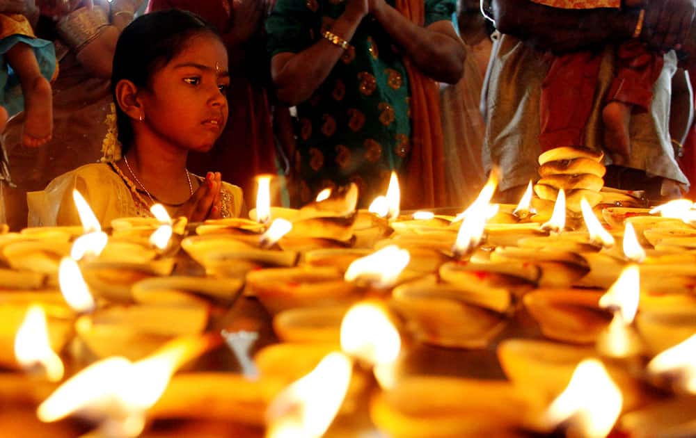 A Hindu devotee offers a prayer in front of oil lamps during Diwali, or the Hindu festival of lights at Batu Caves Hindu temple in Kuala Lumpur, Malaysia.