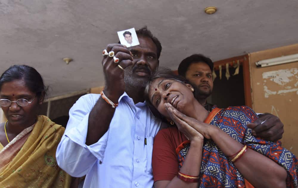Sarala, mother of Raghuveer, photograph displayed by a relative, who was killed in bus fire accident weeps outside the mortuary of Osmania General Hospital in Hyderabad.