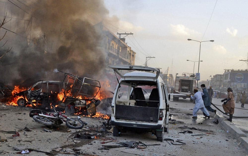Pakistani firemen extinguish a fire on a burning vehicle at the site of a bomb blast in a market in Quetta.