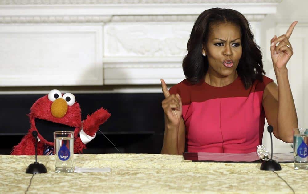 First lady Michelle Obama with PBS Sesame Street`s character Elmo, left, speaks during an event to help promote fresh fruit and vegetable consumption to kids in the State Dining Room of the White House in Washington.