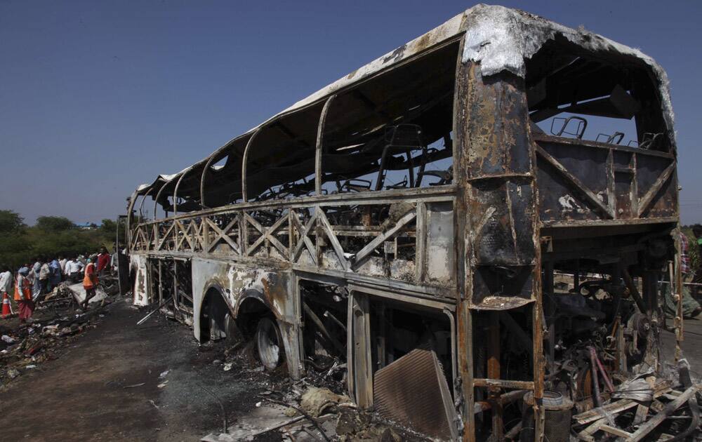 Rescuers and others stand near the debris after a bus crashed into a highway barrier and erupted in flames at Mehabubnagar in southern Andhra Pradesh. According to officials many of the passengers were burned alive in the accident that happened early Wednesday.
