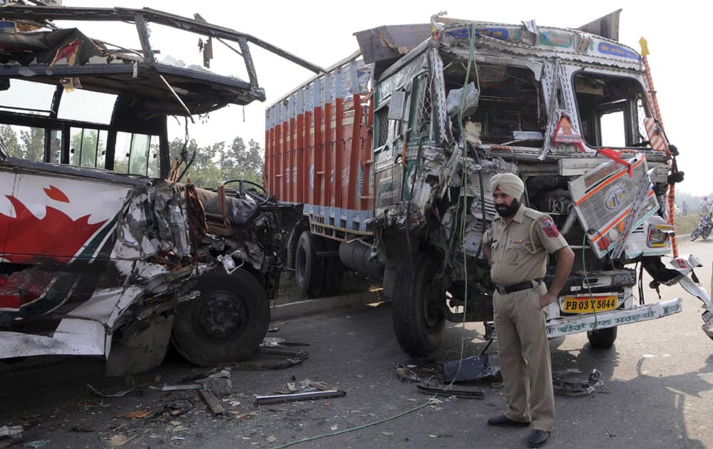 A policeman stands by the site of an accident on a highway near Amritsar. A bus and a truck collided Tuesday killing 8 people, including a child and two women, and injuring more than a dozen.