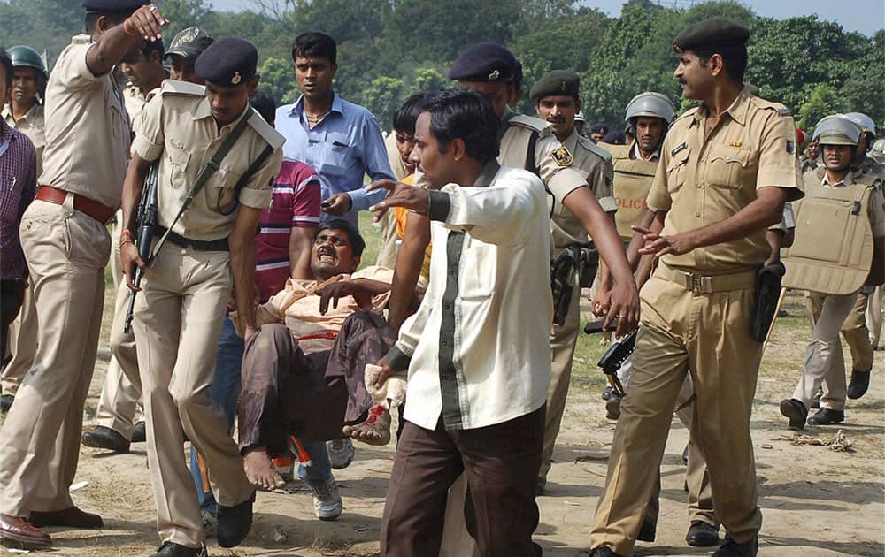 A man injured in bomb blasts is carried by policemen for treatment outside the venue of a political rally in Patna.