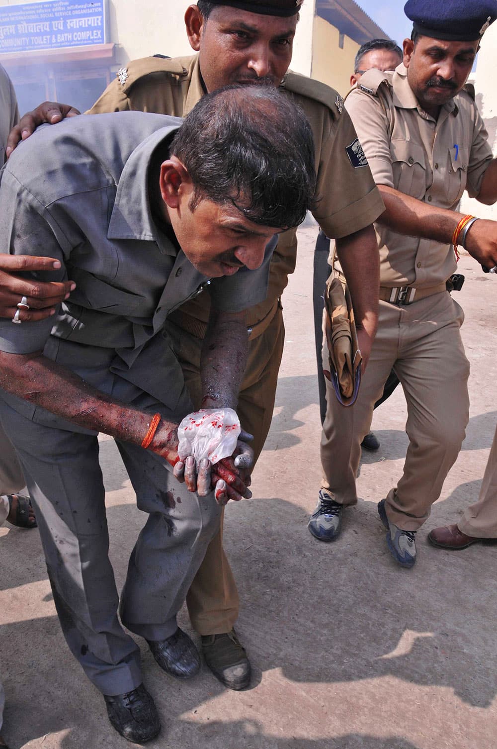 Indian security persons attend to an injured bomb disposal squad member left, after one of the bombs they were trying to defuse exploded in a public toilet building in Patna.