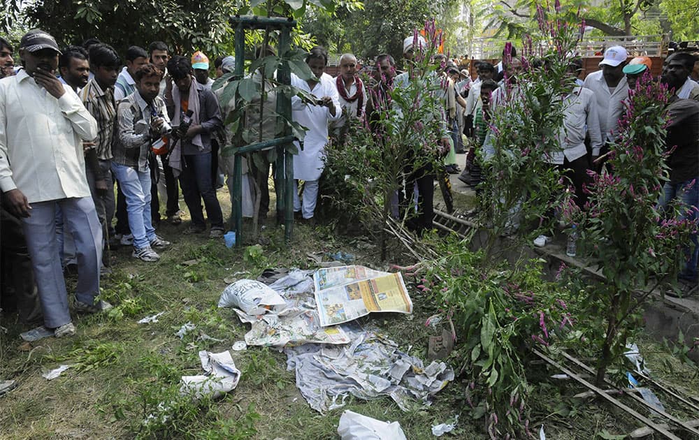 People gather very close to an unexploded bomb, hidden beneath newspapers before it was defused by officials outside the venue of a political rally in Patna.