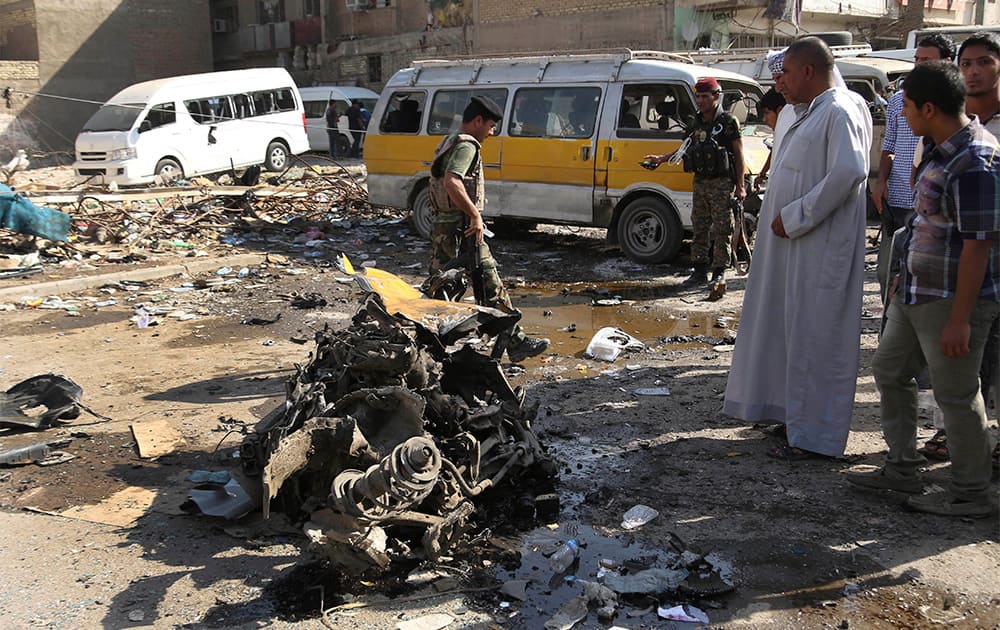 Citizens and security forces inspect the site of a car bomb attack at a bus station in the Baghdad`s eastern Mashtal neighborhood, Iraq.