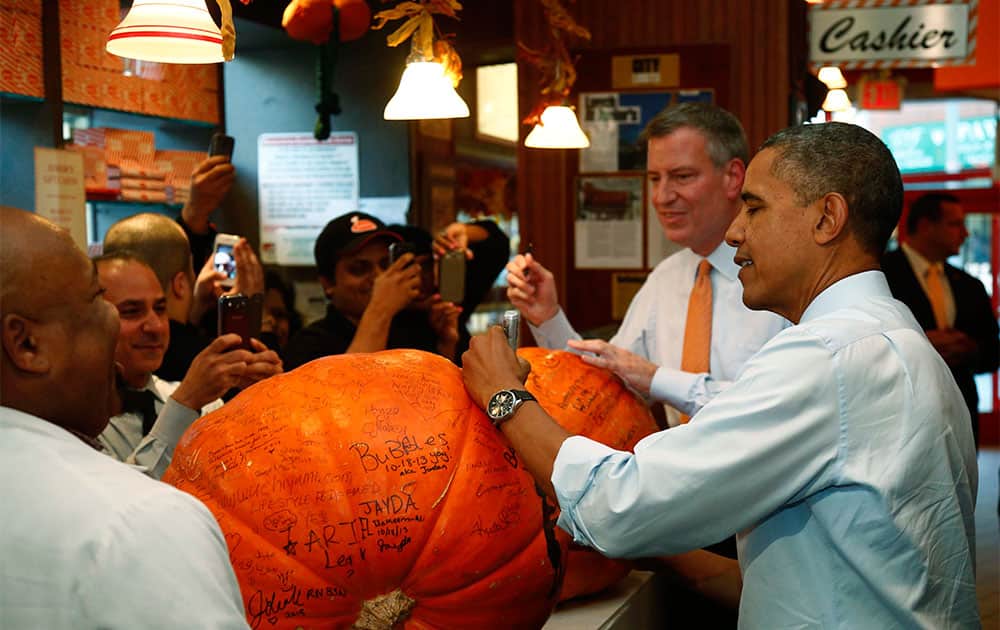 President Barack Obama and New York City Democratic Mayoral Candidate Bill de Blasio sign pumpkins as they visit Junior`s Cheesecake restaurant in the Brooklyn borough of New York.
