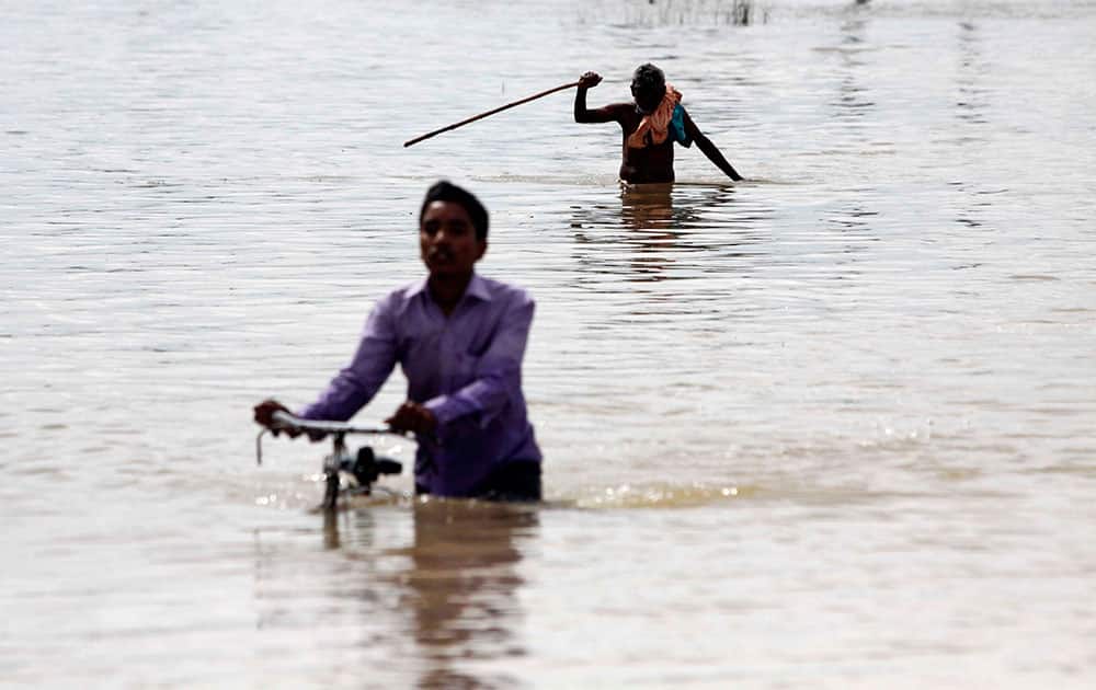 An Indian villager pushes his bicycle as an elderly man negotiates his way through floodwaters in Ganjam district of Orissa state, India.