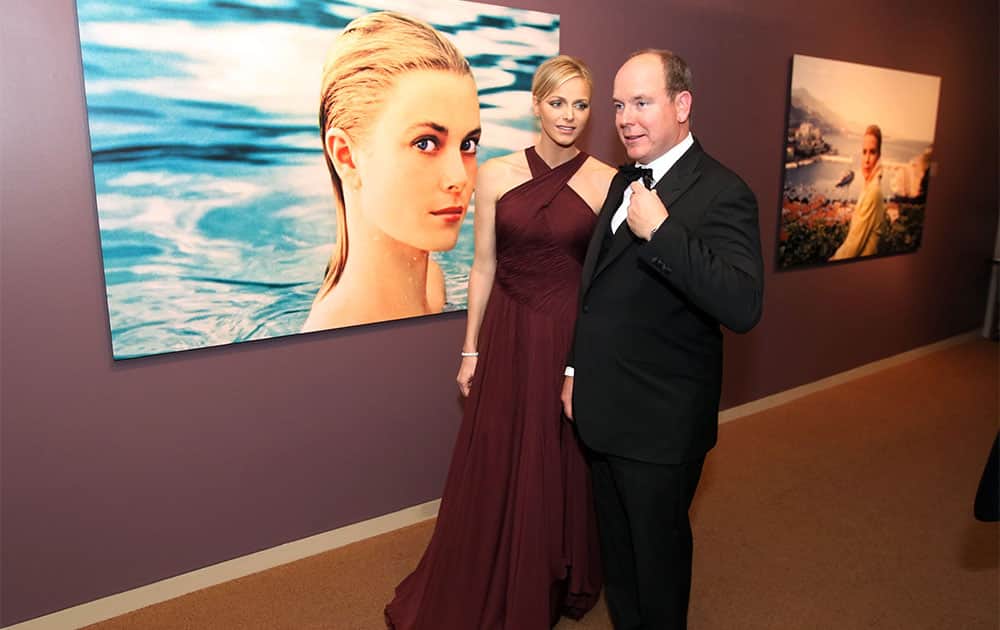 With a large photograph of his mother, when she was an actress in Hollywood, looking on Prince Albert II of Monaco, right, and his wife, Charlene, Princess of Monaco walk through the Grace Kelly exhibit at the James Mitchner Library in Doylestown, Pa.