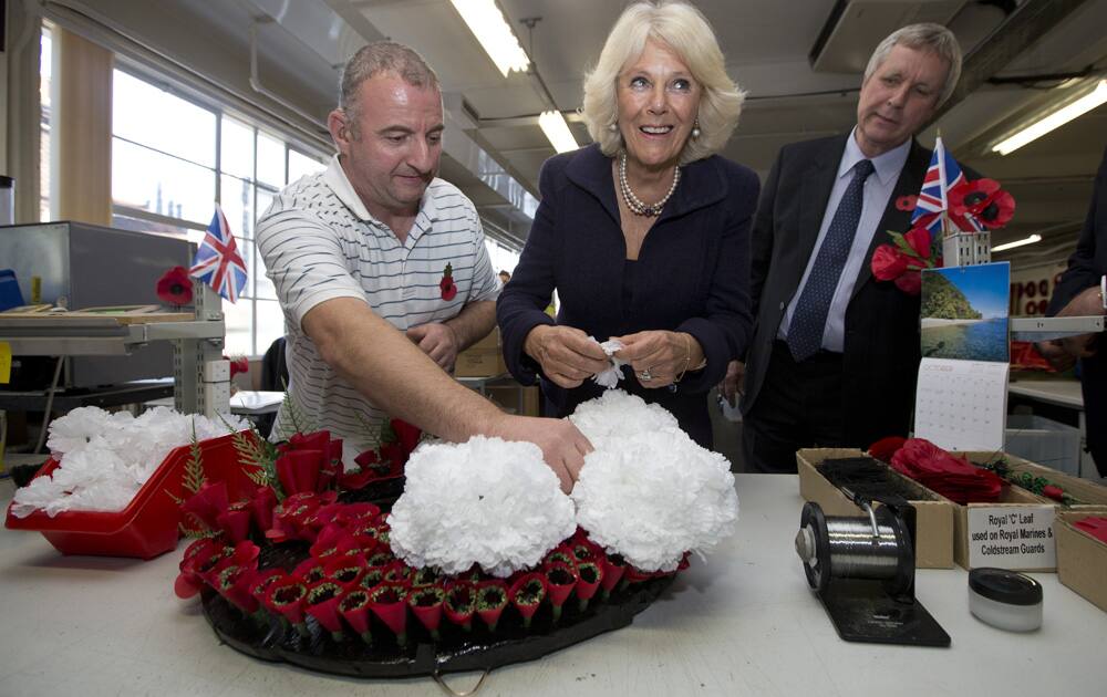 Camilla, the Duchess of Cornwall helps employee Peter Wills, left, put the finishing touches to the poppy wreath that Britain`s Prince Charles will lay on Armistice Day, while on his official visit to India, at the Poppy factory in London.