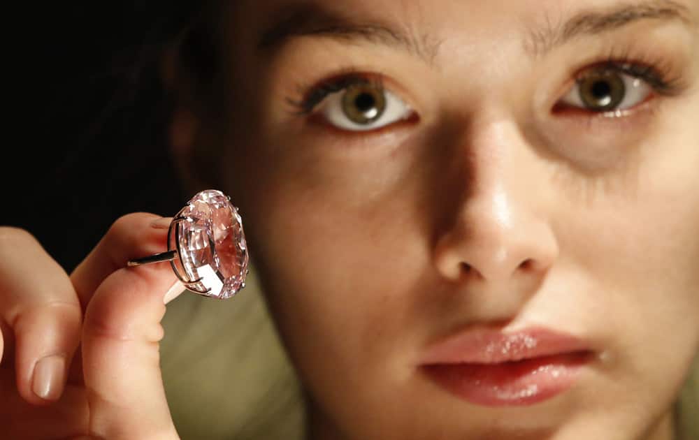 Model Annabeth Murphy-Thomas poses for photographers holding a ring with the Pink Star, a 59.6-carat oval cut internally flawless fancy vivid pink diamond, ahead of its auction in central London.