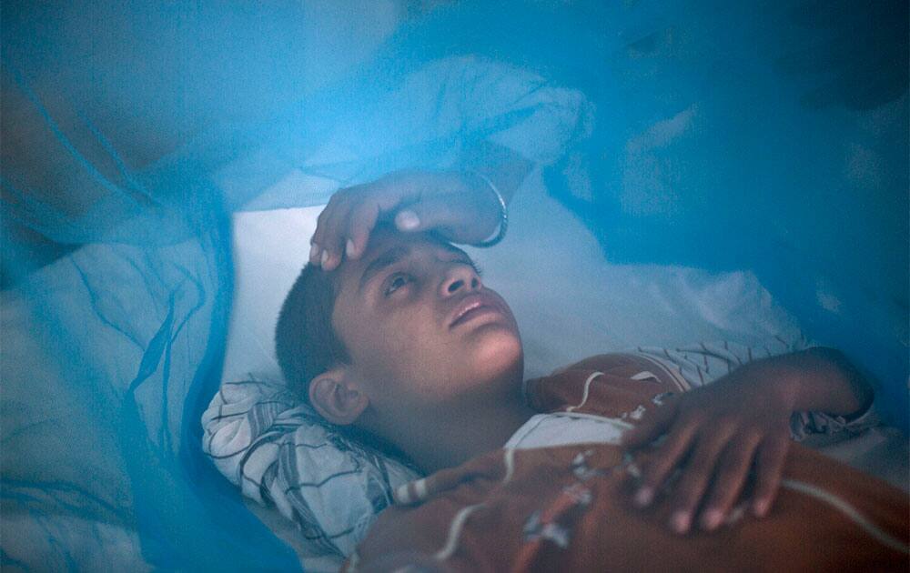 Pakistani boy, Awais Shaukat, 13, suffering from the mosquito-borne disease, dengue fever, is comforted by his father Shaukat while lying in bed covered with a net at an isolation ward of a hospital in Rawalpindi, Pakistan.