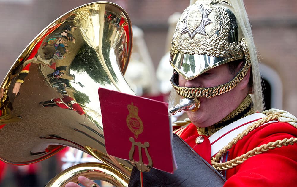 Tourists are reflected in the brass of a member of the Life Guards band as they escort a Colour party of the Grenadier Guards as they leave St James`s Palace to change the guard at Buckingham Palace in London.