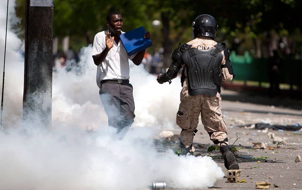 Engulfed in a cloud of tear gas, a student is briefly detained by police during a protest in Port-au-Prince, Haiti.