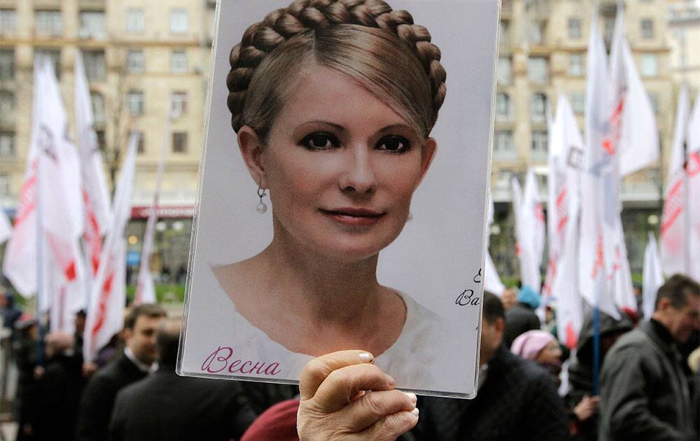 An activist of the Ukrainian Opposition Party holds a poster with a photo of former Ukrainian Prime Minister Yulia Tymoshenko outside the Kiev city council building, during a protest rally demanding a re-election of the city council, in Kiev, Ukraine.
