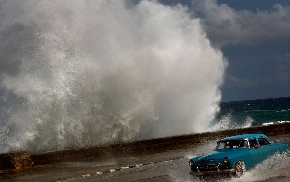 A classic American car drives along a wet road as a wave crashes against the Malecon in Havana, Cuba. The following night, Sandy had passed the Bahamas and was being enveloped by an ordinary cold front coming off the Southeast.