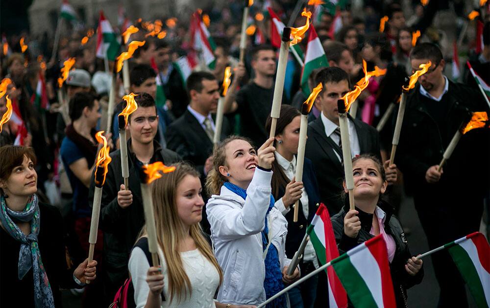Young people hold torches and wave national flags as they march through the streets of Budapest to re-enact the protest march of Hungarian students in 1956, which ignited the revolution and war of independence against communist rule and the Soviet Union, the eve of the 57th anniversary of the outbreak of the 1956 revolution.