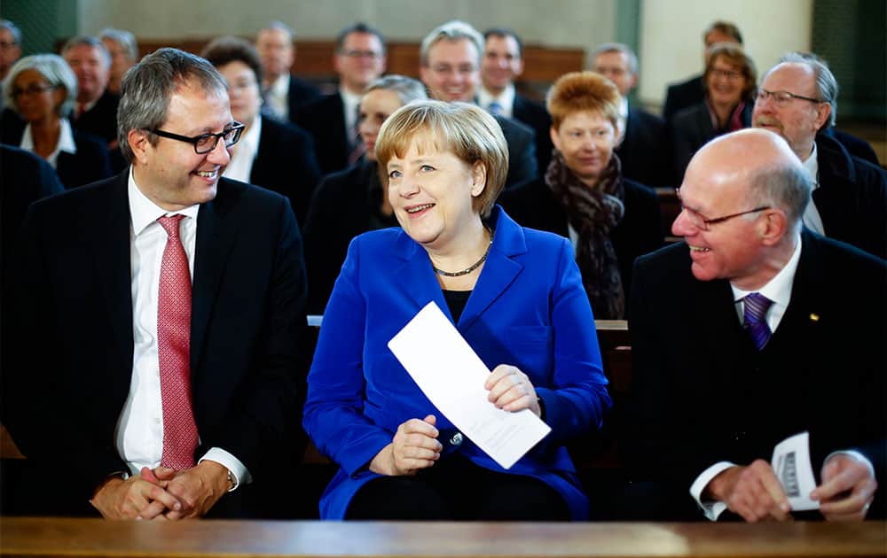 German Chancellor Angela Merkel, center, sits between Andreas Vosskuhle, left, president of the Federal Constitutional Court of Germany and Parliament President Norbert Lammert, right, as she attends an ecumenical service prior to a constitute session of the German parliament Bundestag in Berlin.