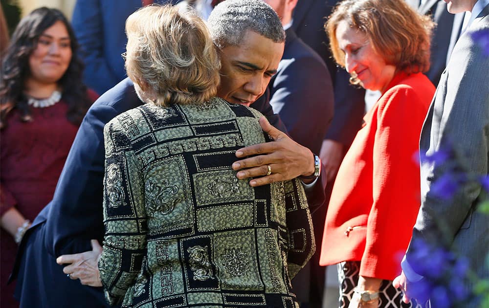 President Barack Obama hugs Janice Baker, who runs a small business in Selbyville, Del., and was the first woman to enroll in the Delaware health care exchange, during an event in the Rose Garden of the White House in Washington.