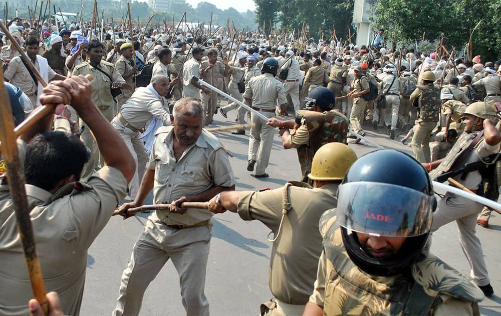 Members of the Indian Home Guard force, without caps and holding batons, clash with police, seen wearing helmets, during a protest demanding regularization of their jobs in Lucknow.