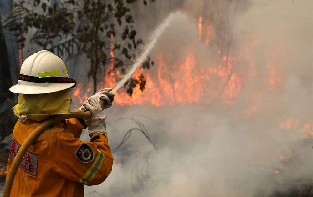 A firefighter tries to control flames near houses at Bilpin, 75 kilometers (47 miles) west of Sydney, Australia.