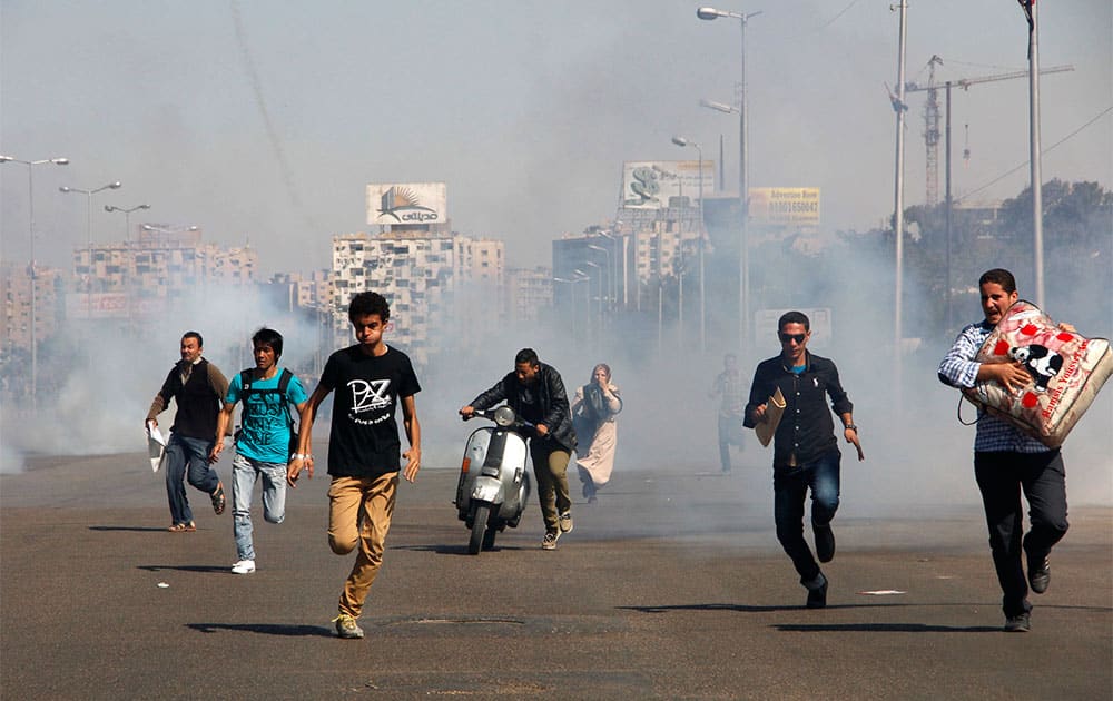 Egyptians run from tear gas after clashes erupted between Al-Azhar students and police forces during a protest in the Nasr City district of Cairo.