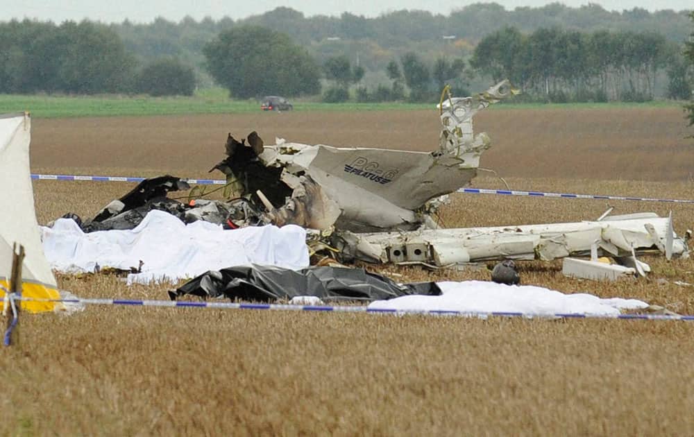 Bodies are covered near the debris of a small plane which crashed in a field in Marchovelette, Belgium. The plane, carrying parachutists for a skydiving trip, crashed killing all 11 people aboard, officials said.