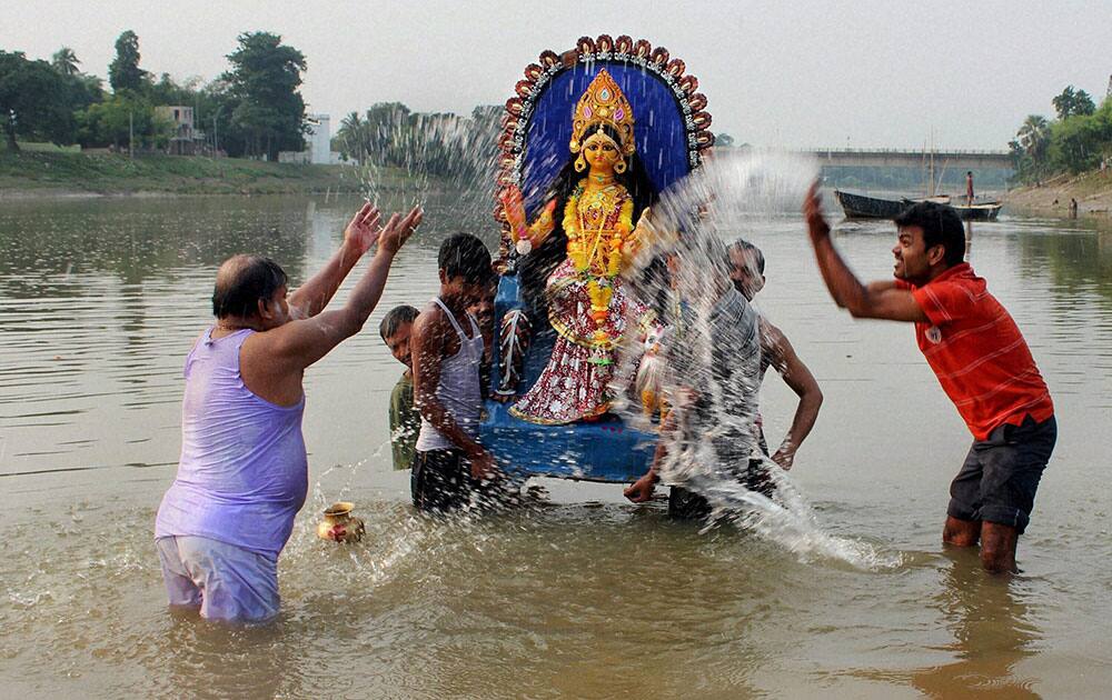 Devotees Immerse an idol of Goddess Lakshmi in the bank of river Atreyee after Lakshmi Puja at Balurghat in South Dinajpur district of West Bengal.