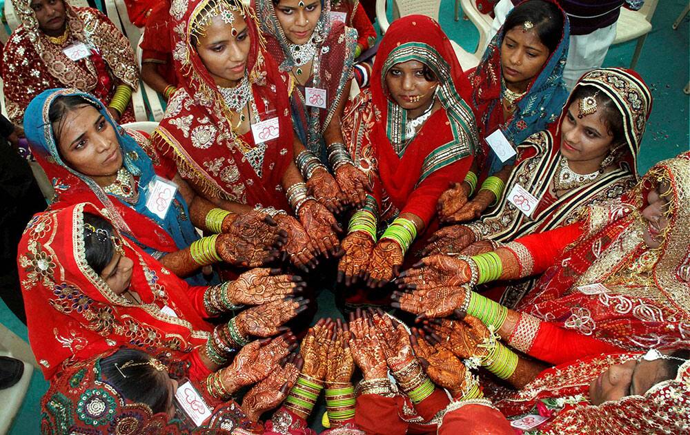Muslim brides show their hands decorated with henna paste as they wait for the start of a mass marriage ceremony in Ahmedabad.