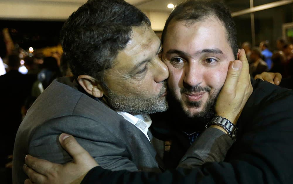 Ali Abbas, right, one of nine released Lebanese Shiite pilgrims who were kidnapped by a rebel faction in northern Syria in May 2012, right, is kissed by his relative upon his arrival at Rafik Hariri international airport, in Beirut, Lebanon. Two Turkish pilots held hostage in Lebanon and nine Lebanese pilgrims abducted in Syria returned home Saturday night, part of an ambitious three-way deal cutting across the Syrian civil war.