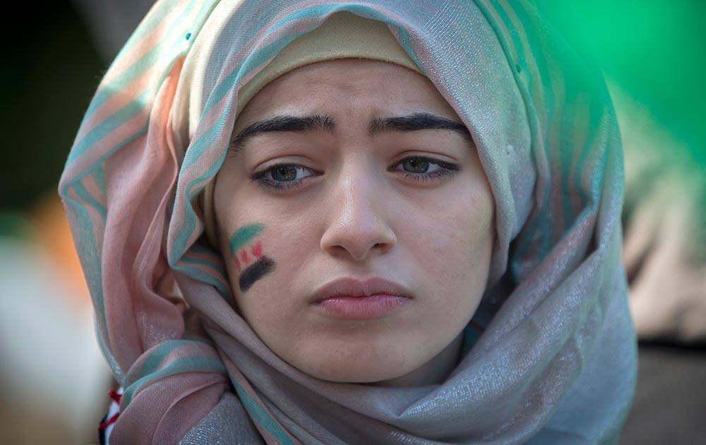 A girl with a Syrian flag painted on her face attends a protest by members of the Syrian community in Bucharest, Romania.