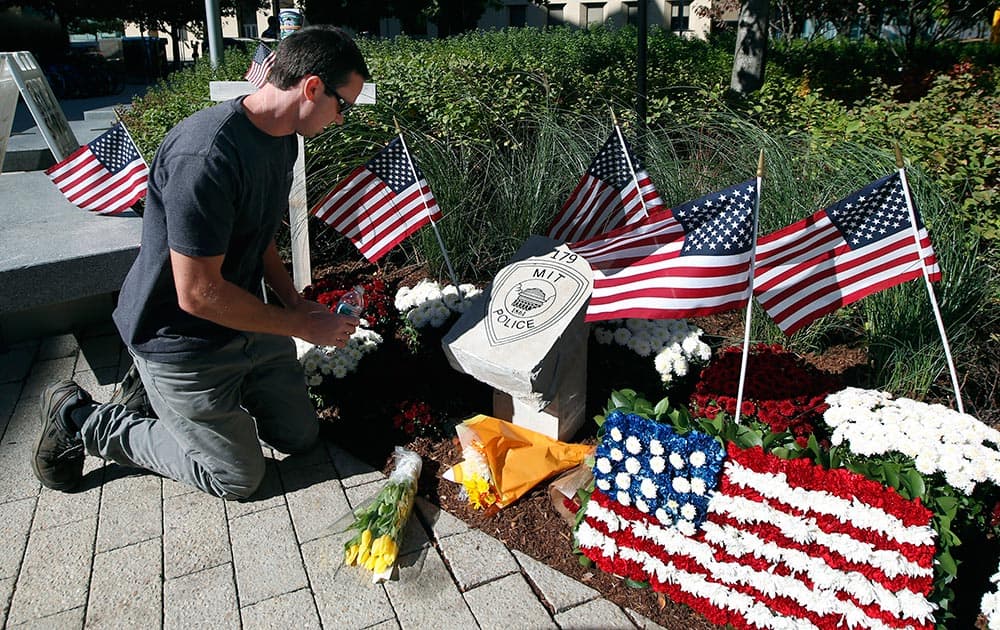 Tim Brignolo, of the Massachusetts Institute of Technology facilities department, waters the flowers at a temporary memorial to slain MIT police Officer Sean Collier in Cambridge, Mass.