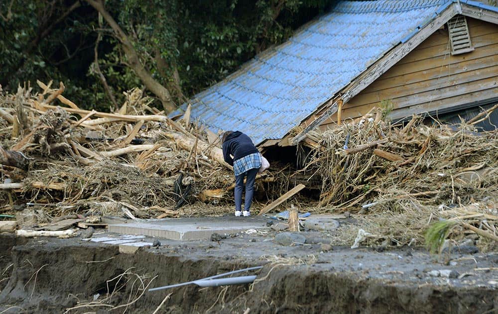 A woman tries to check inside of a damaged house in Oshima after a powerful typhoon hit Izu Oshima island, about 120 kilometers (75 miles) south of Tokyo.
