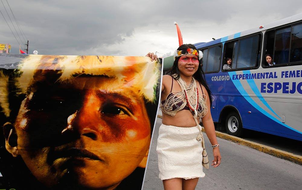 An Amazon Indian woman holds the edge of a poster as she marches in a protest against the extraction of oil from the Yasuni National Park, in Quito, Ecuador.