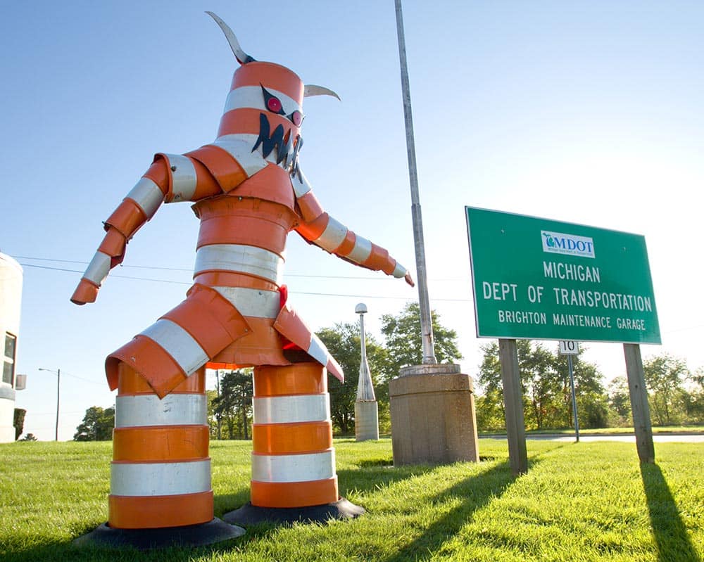 A monster constructed from traffic cones by garage workers looms over drivers passing along Grand River near Old U.S. 23 in front of the MDOT Brighton Maintenance Garage.