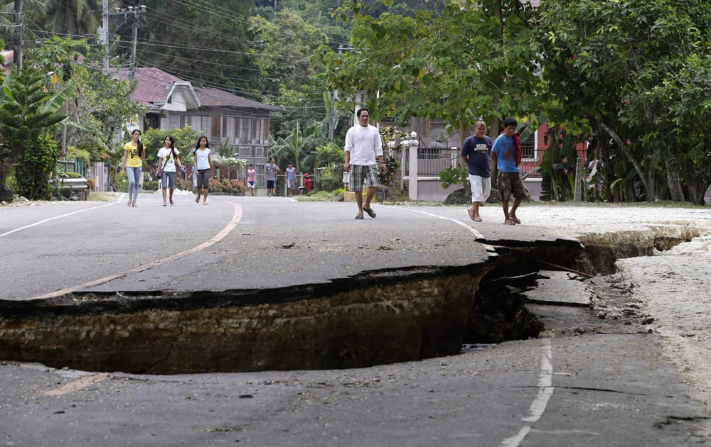 Residents walk on a damaged highway in Loboc township, Bohol province in central Philippines, a day after a 7.2-magnitude quake hit Bohol and Cebu provinces.