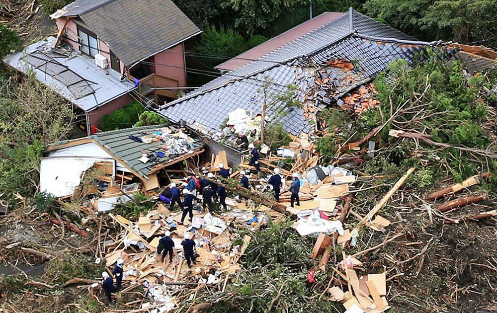 Rescue workers look for survivors as they stand on the rubble of a house buried by mudslides after a powerful typhoon hit Oshima on Izu Oshima island, about 120 kilometers south of Tokyo.