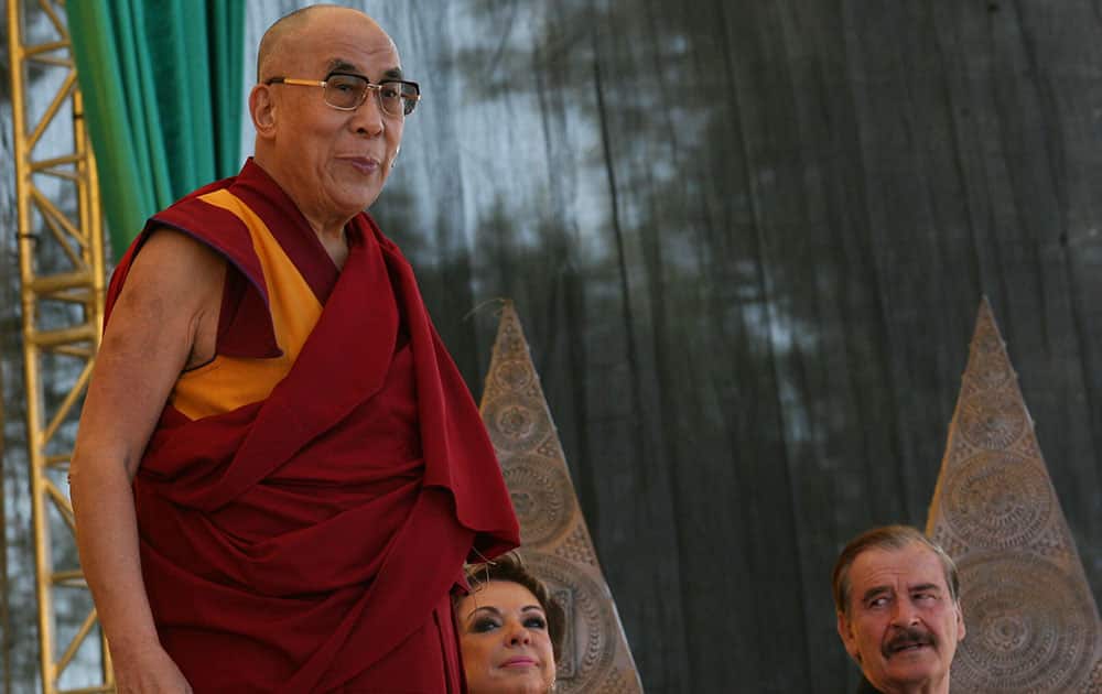 The Dalai Lama, stands on the stage as Mexico`s former President Vicente Fox and his wife, Marta Sahagun watch in San Cristobal, Mexico.