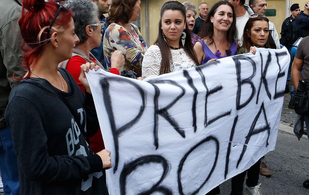 Demonstrators hold up a sheet with writing reading in Italian