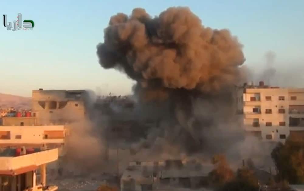 This image taken from video obtained from the Shaam News Network, which has been authenticated based on its contents and other AP reporting, smoke billows amid buildings at a bomb explosion in Daraya, a countryside of Damscus, Syria.
