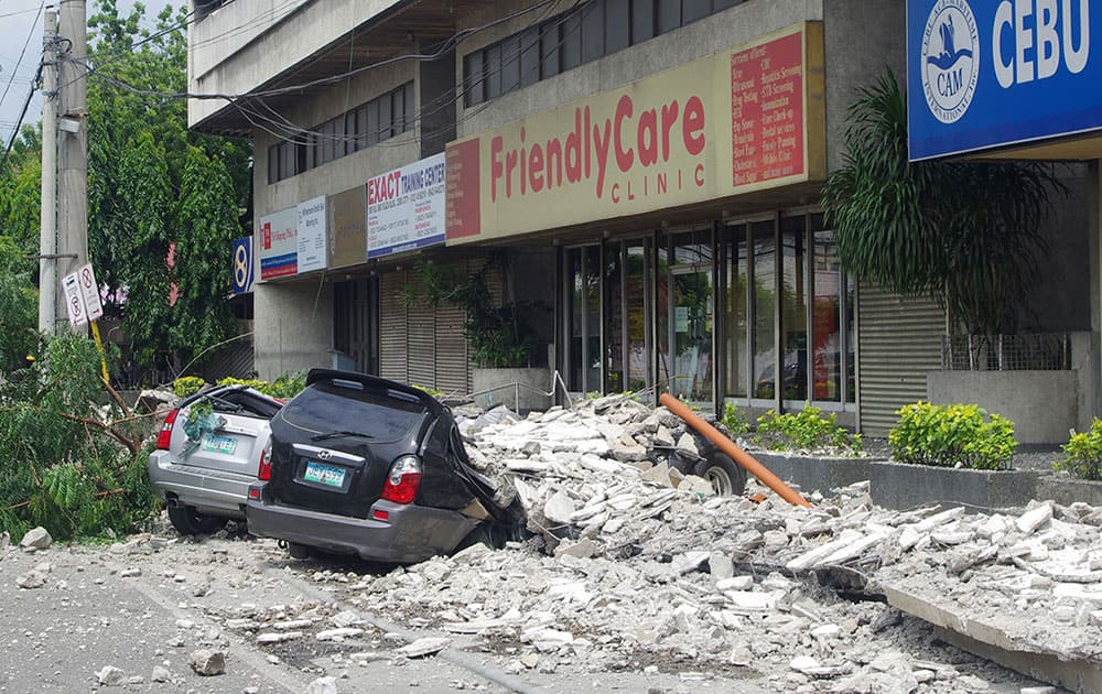 Damaged cars lie under a rubble outside the GMC Plaza Building in Cebu, central Philippines. A 7.2-magnitude earthquake collapsed buildings, cracked roads and toppled the bell tower of the Philippines` oldest church Tuesday morning, killing at least 20 people across the central region.
