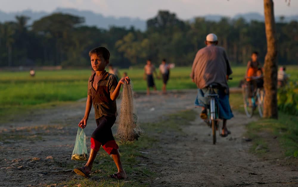 A Muslim child walks with a net and some fish in a bag close to Myinn Hlut village, Maungdaw, Rakhine state, Myanmar. Children are the biggest victims of policies that for decades have systematically discriminated against Rohingya Muslims.