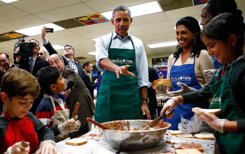 President Barack Obama stops by a table of grade school aged volunteers making peanut butter and jelly sandwiches as he visits Martha`s Table, which assists the poor and where furloughed federal employees are volunteering, in Washington.