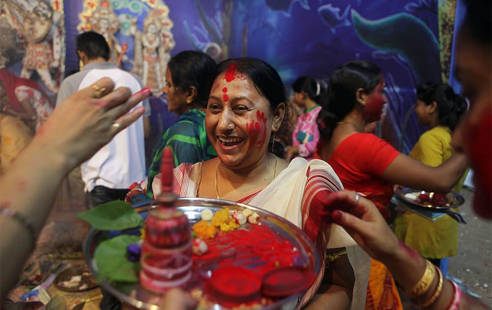 An Indian woman laughs as others prepare to apply vermilion on her on the last day of Durga Puja festivities in Gauhati, India.