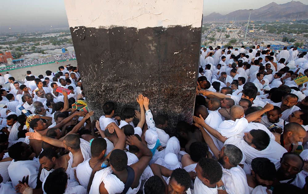 Muslim pilgrims pray on a rocky hill called the Mountain of Mercy, some touching a marker at its peak, on the Plain of Arafat, near the holy city of Mecca, Saudi Arabia.