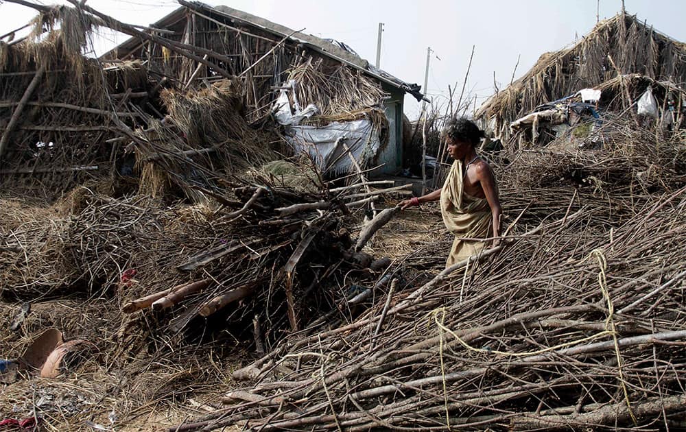An Indian woman walks past damaged houses after returning to a cyclone-hit village in Pudumpeta, Ganjam district, Orissa state.